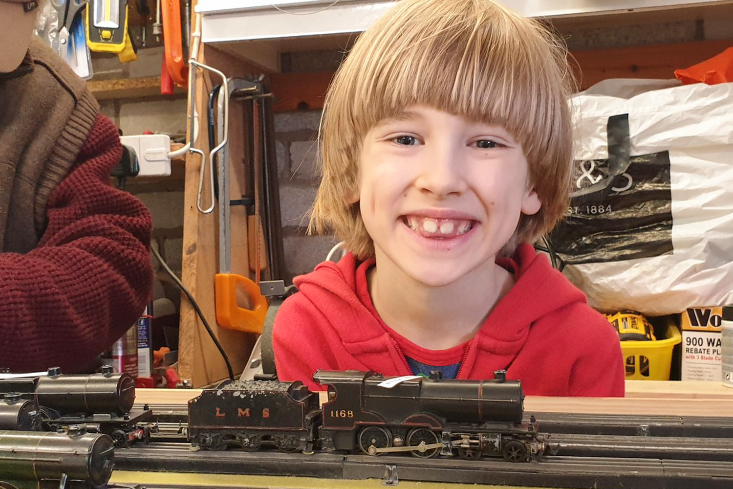 Toby smiling with a model train in front of him