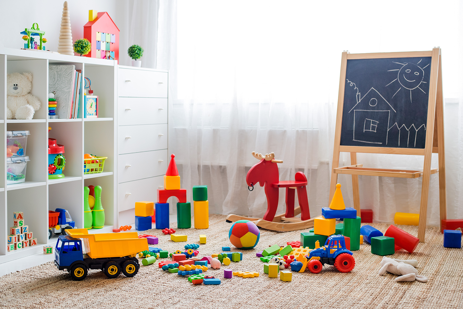 Playroom with cube storage, chalkboard easel and toys on the floor