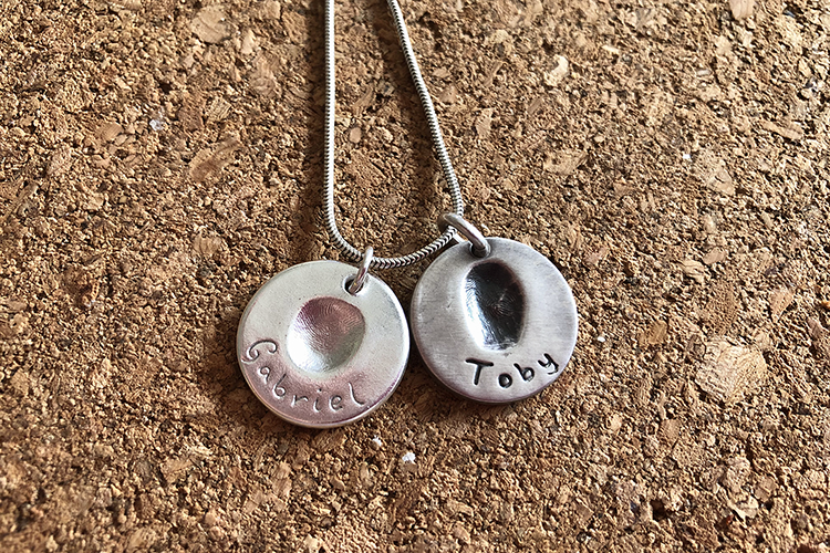 Two silver fingerprint pendants on a chain