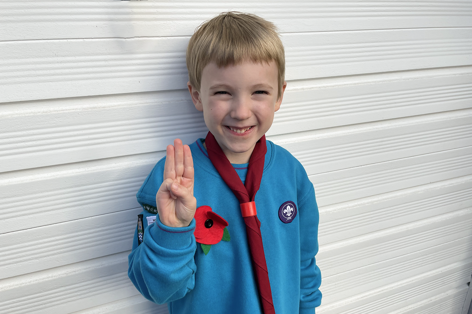 Gabe in his Beaver uniform making the Scout sign, standing in front of a white background